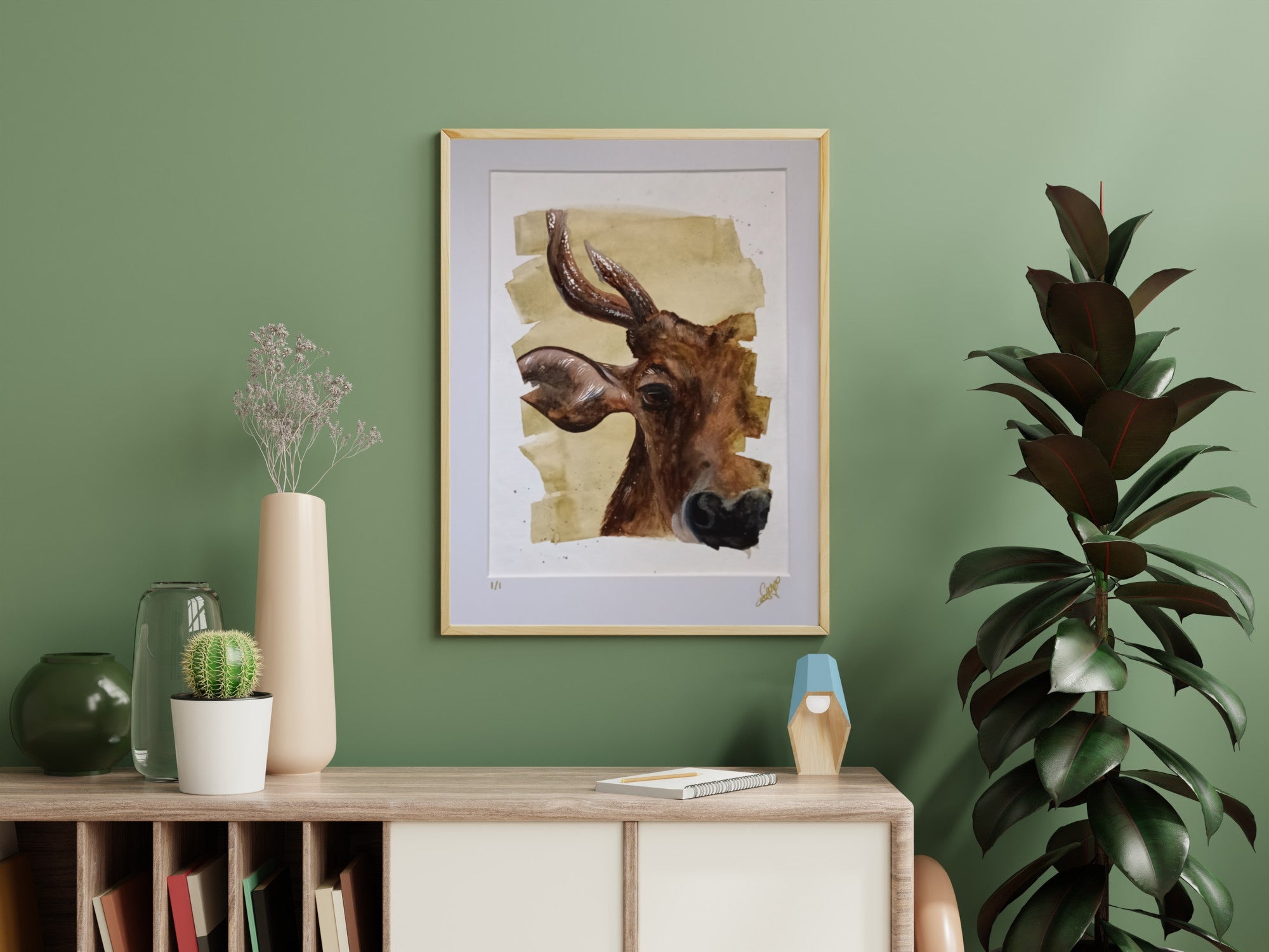 Framed artwork of a cow on a green wall with decorative items below.