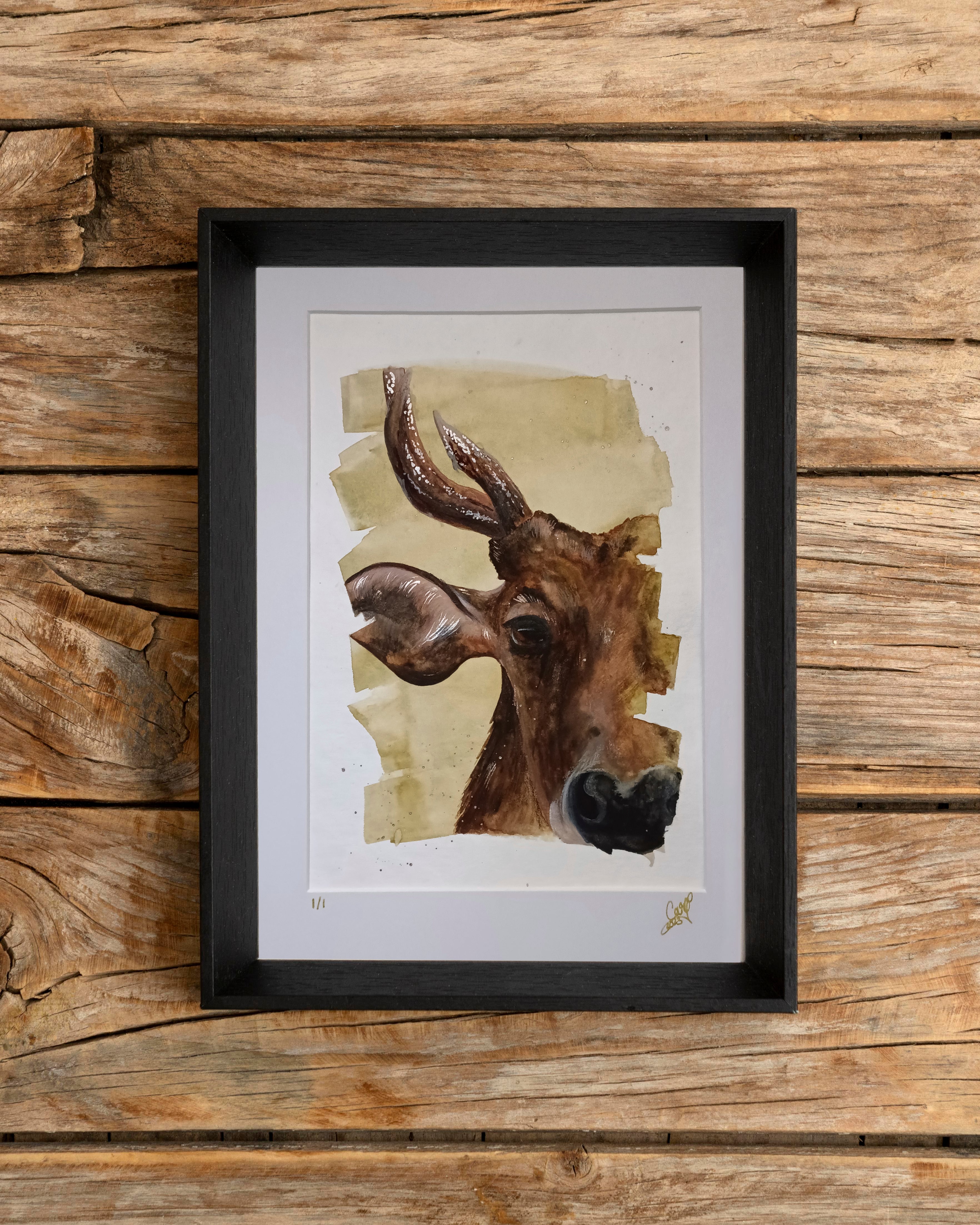 Framed artwork of a watercolour cow head on a wooden background
