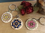 Three decorative keychains showing the three different mandala designs. From left to right: Arches, Tile, Flower.