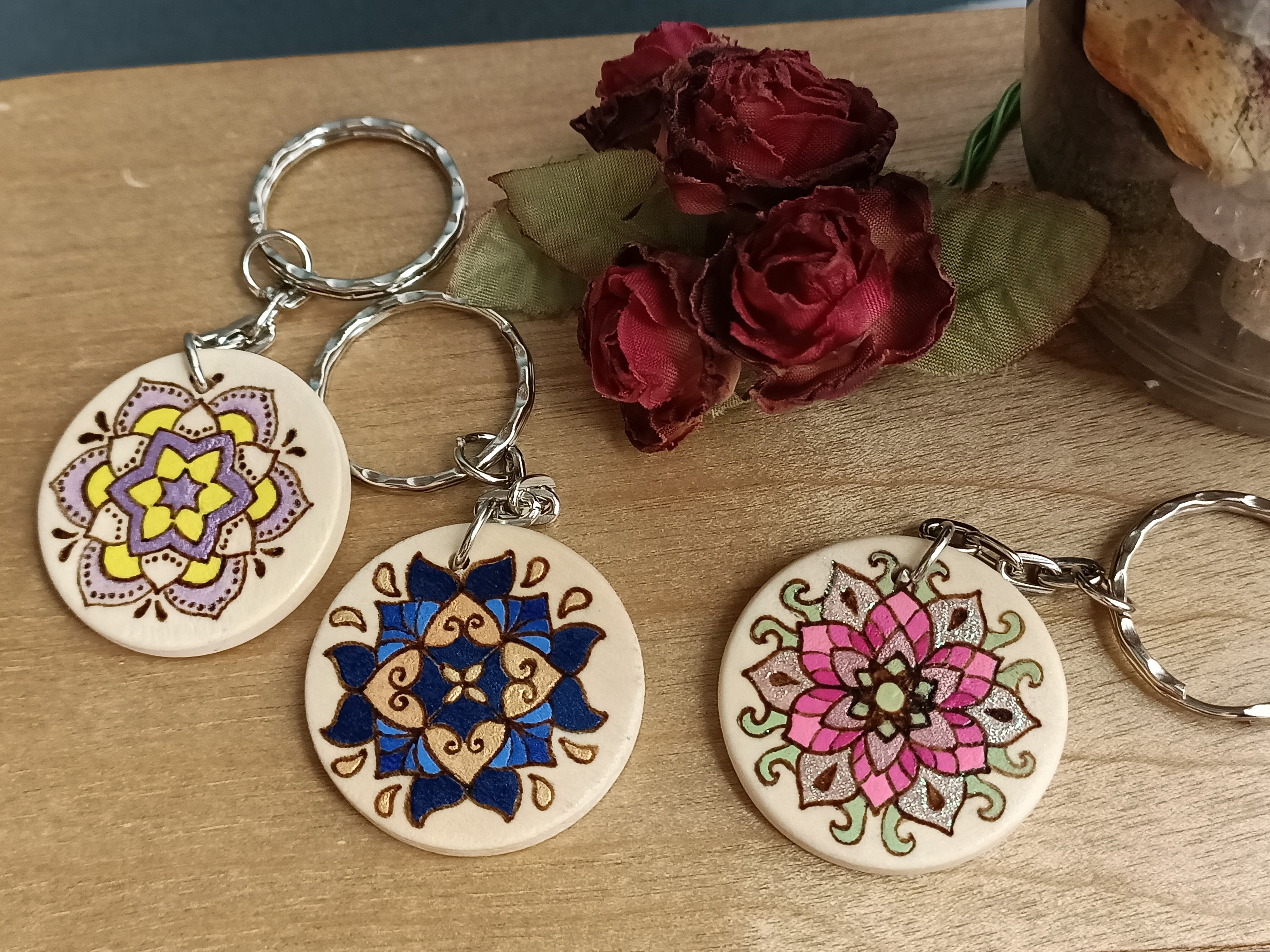 Three decorative keychains showing the three different mandala designs. From left to right: Arches, Tile, Flower.