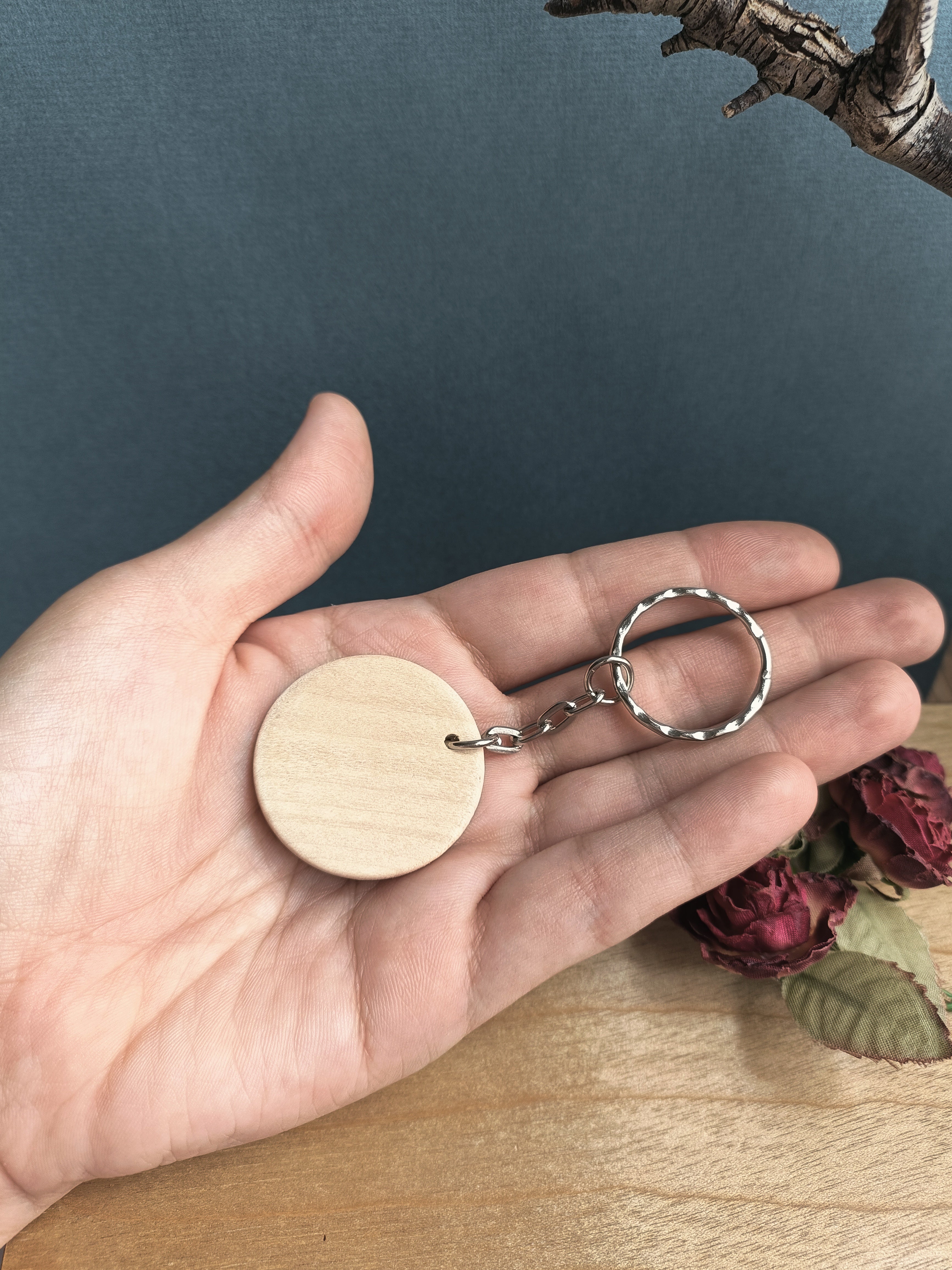 Hand holding the whole keychain in its palm, showing the blank backside of the wooden circle.