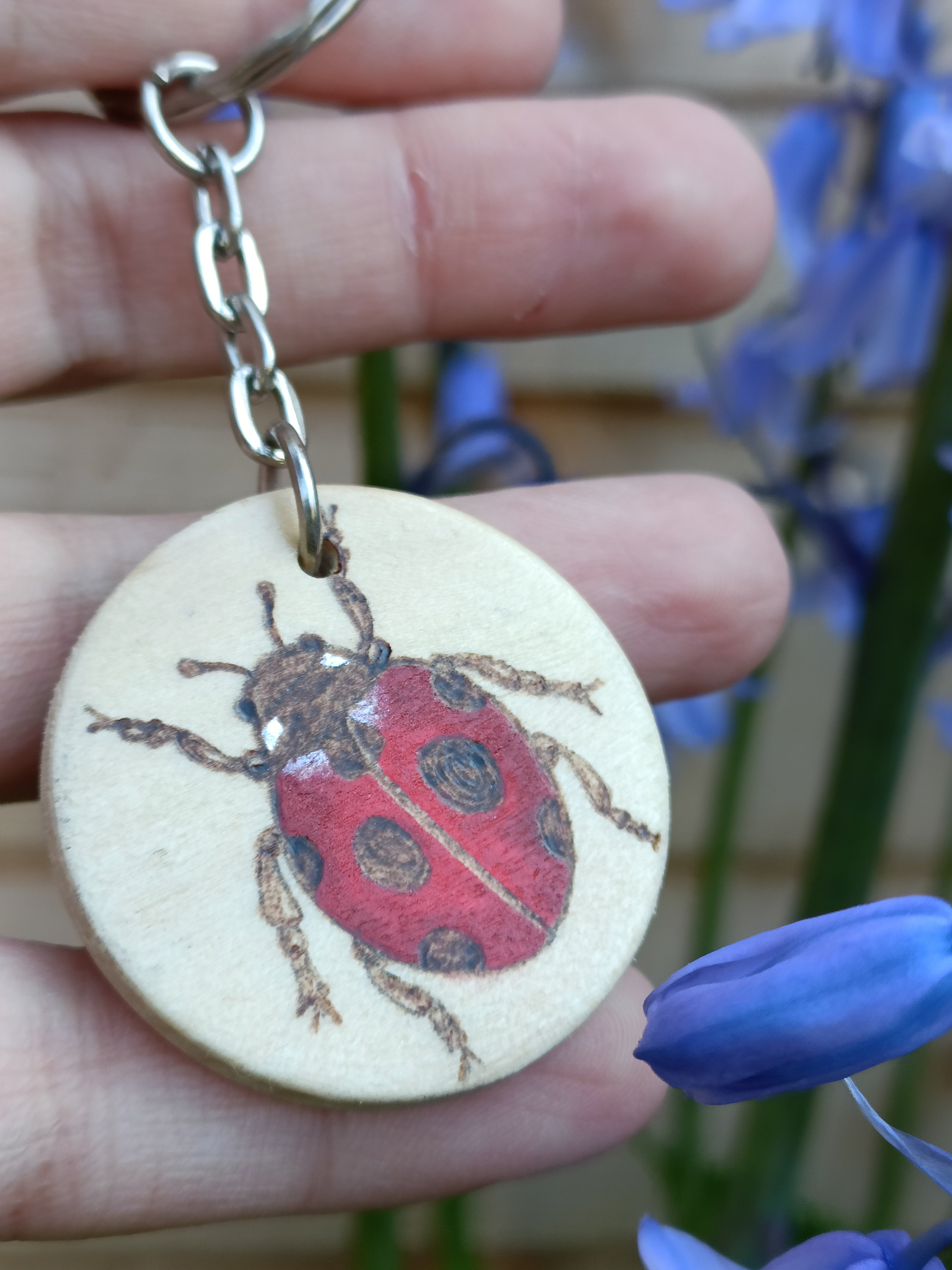 Close-up of woodburned ladybird keyring, showing the burning texture in natural light outside.
