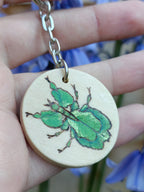 Close-up of thewoodburned and painted walking leaf insect keychain in natural light.