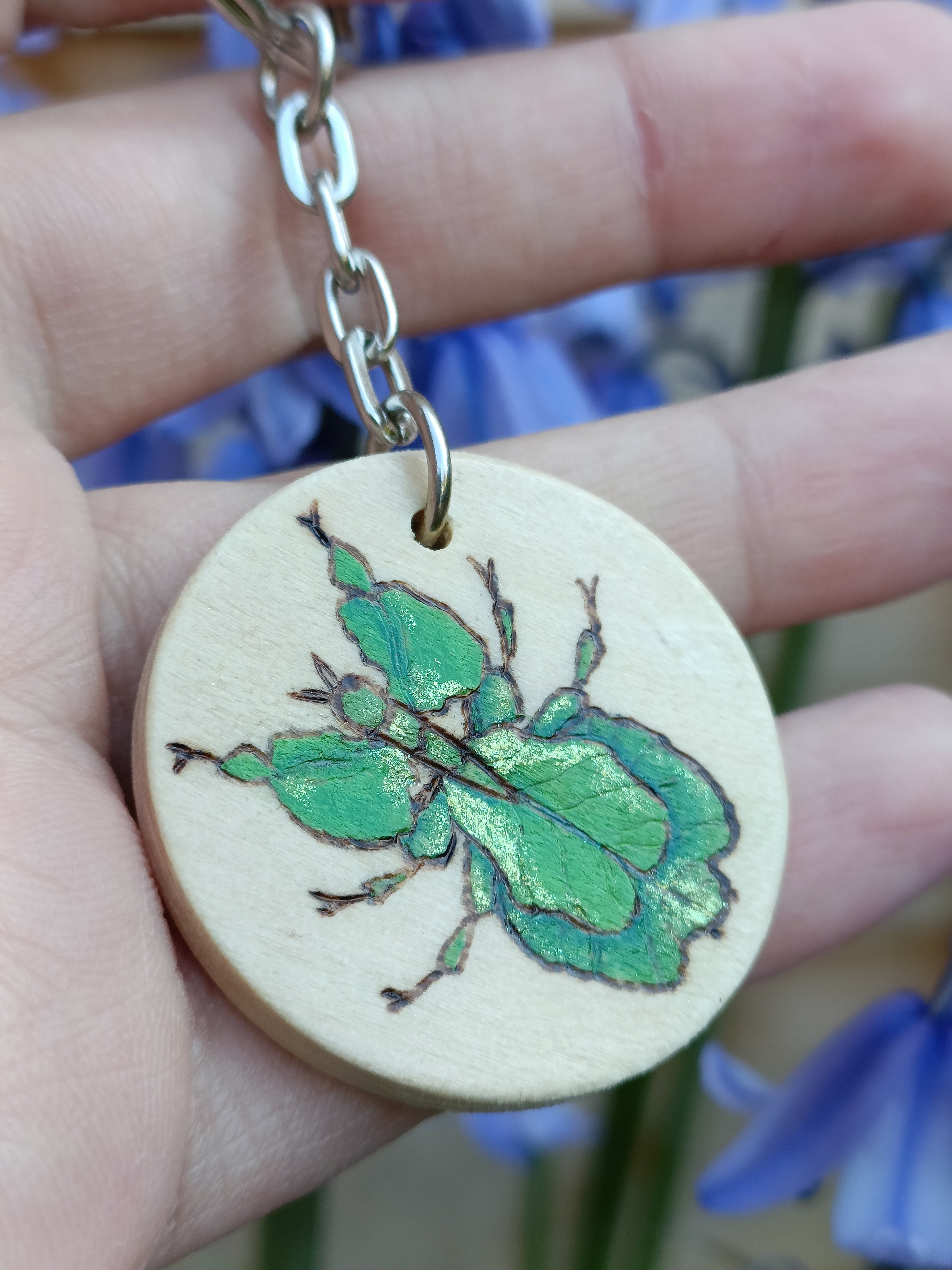 Close-up of thewoodburned and painted walking leaf insect keychain in natural light.