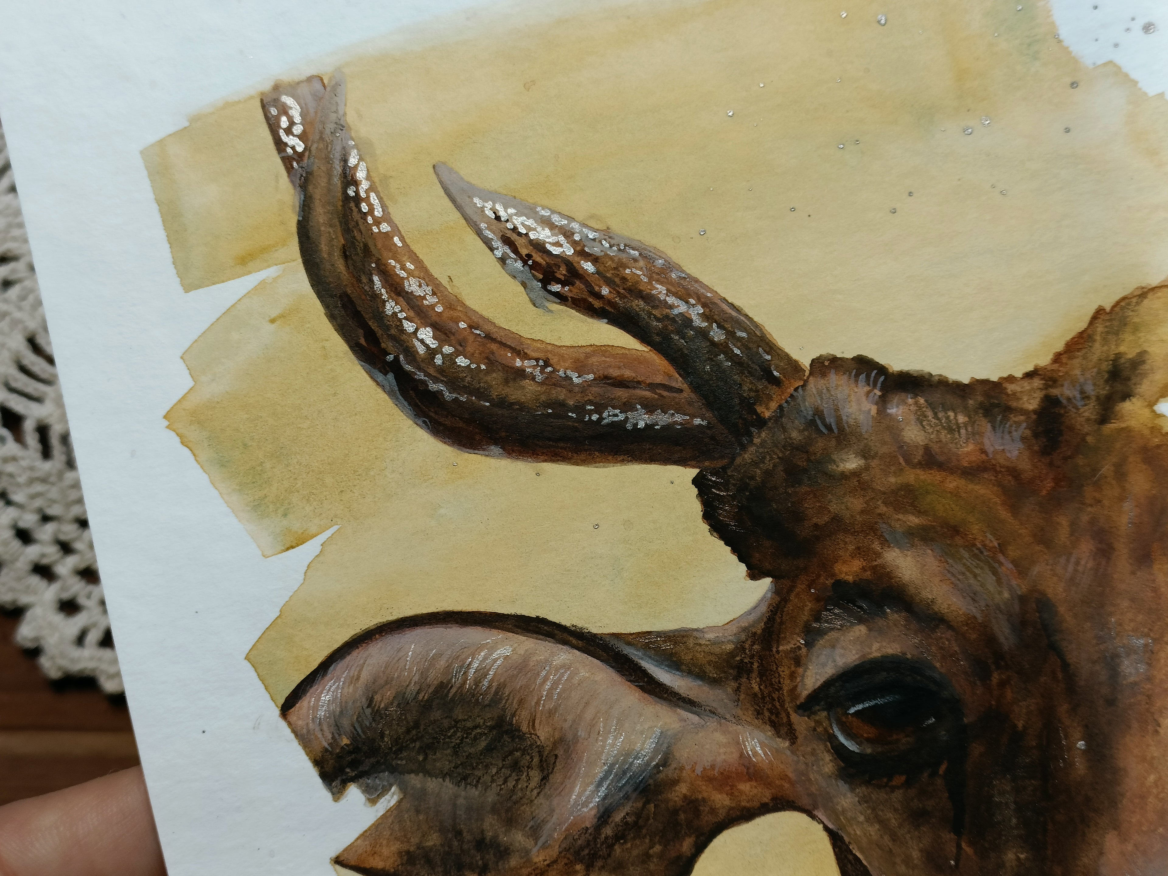 Close-up of the watercolour cow portrait, showing detail work and shimmer accents on horns and ear.