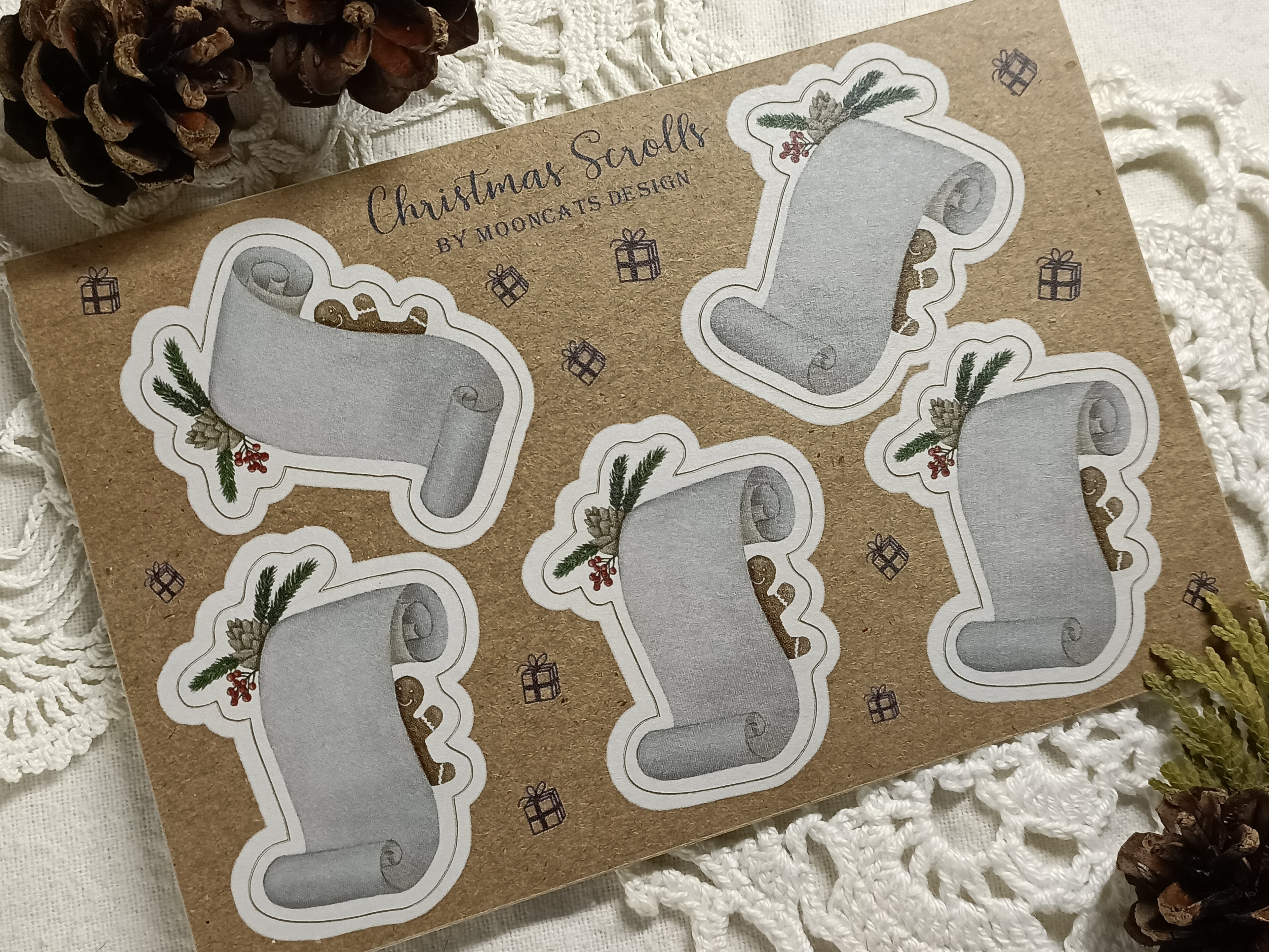 Set of Christmas-themed sticker labels on a kraft paper sheet with decorative elements. These show scrolls with pinecones and gingerbread men.