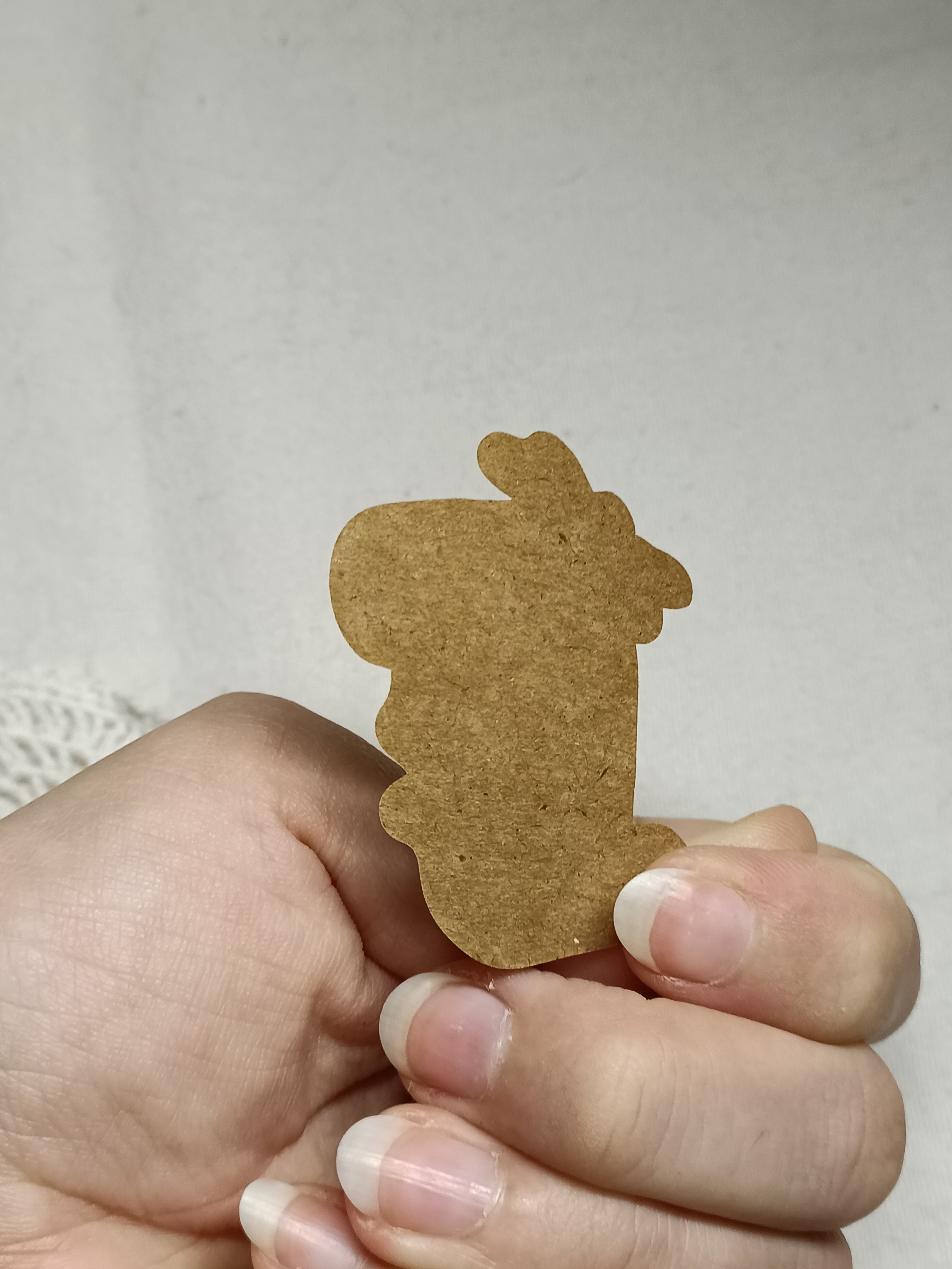 Hand holding one of the kraft label stickers to show the adhesive backside.