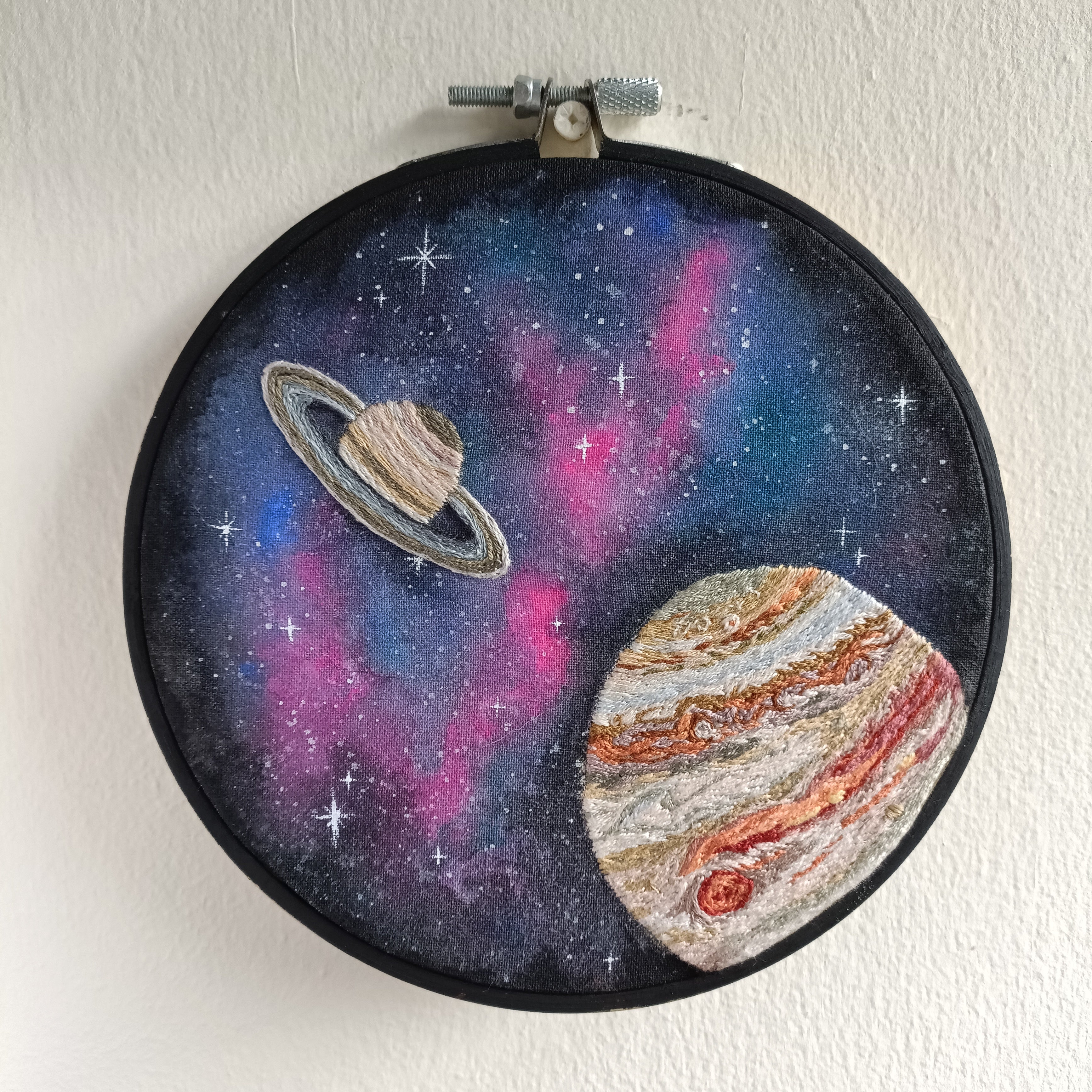 Embroidery hoop with space-themed design featuring Saturn and Jupiter on a starry background.