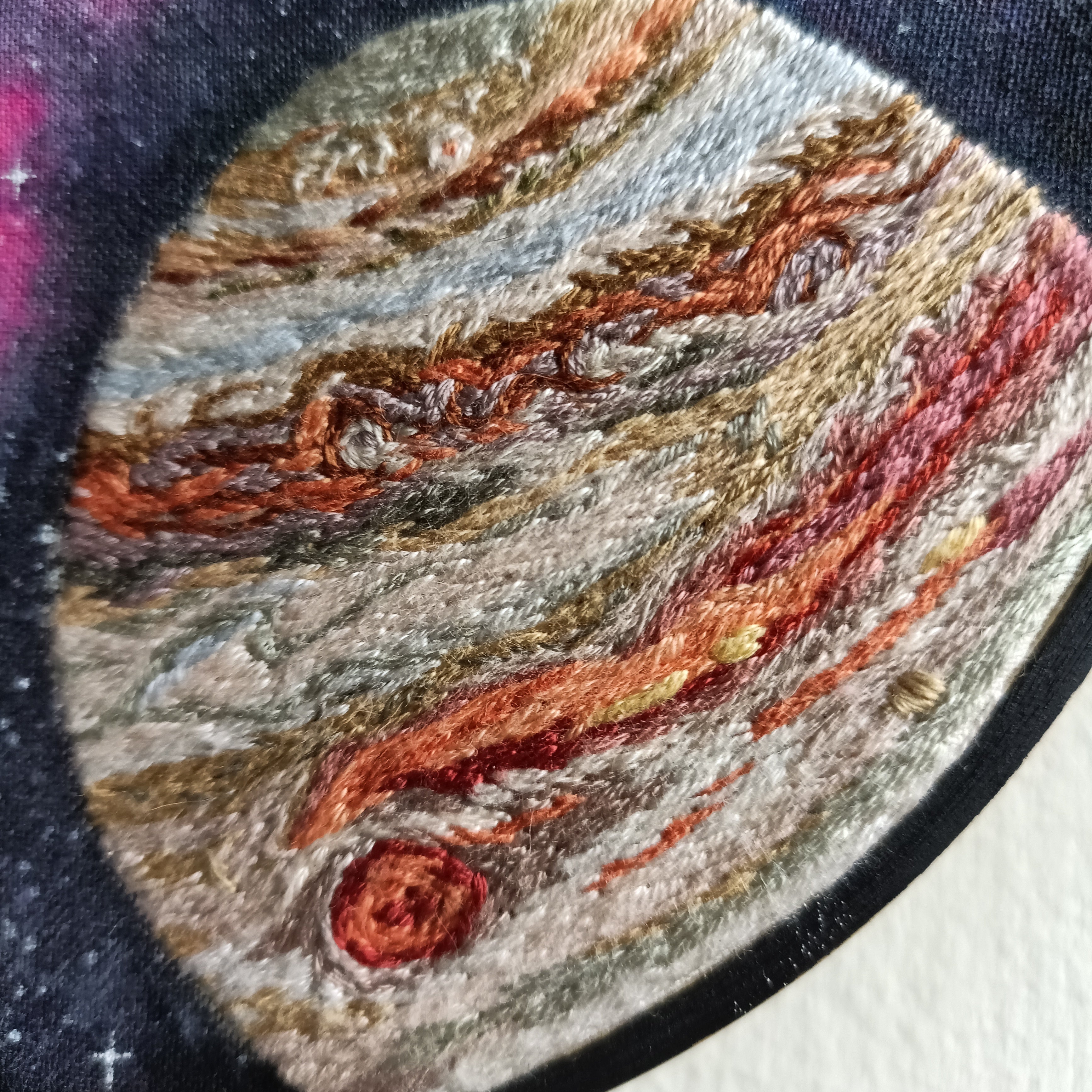 Embroidery of Jupiter with visible texture and colour details.