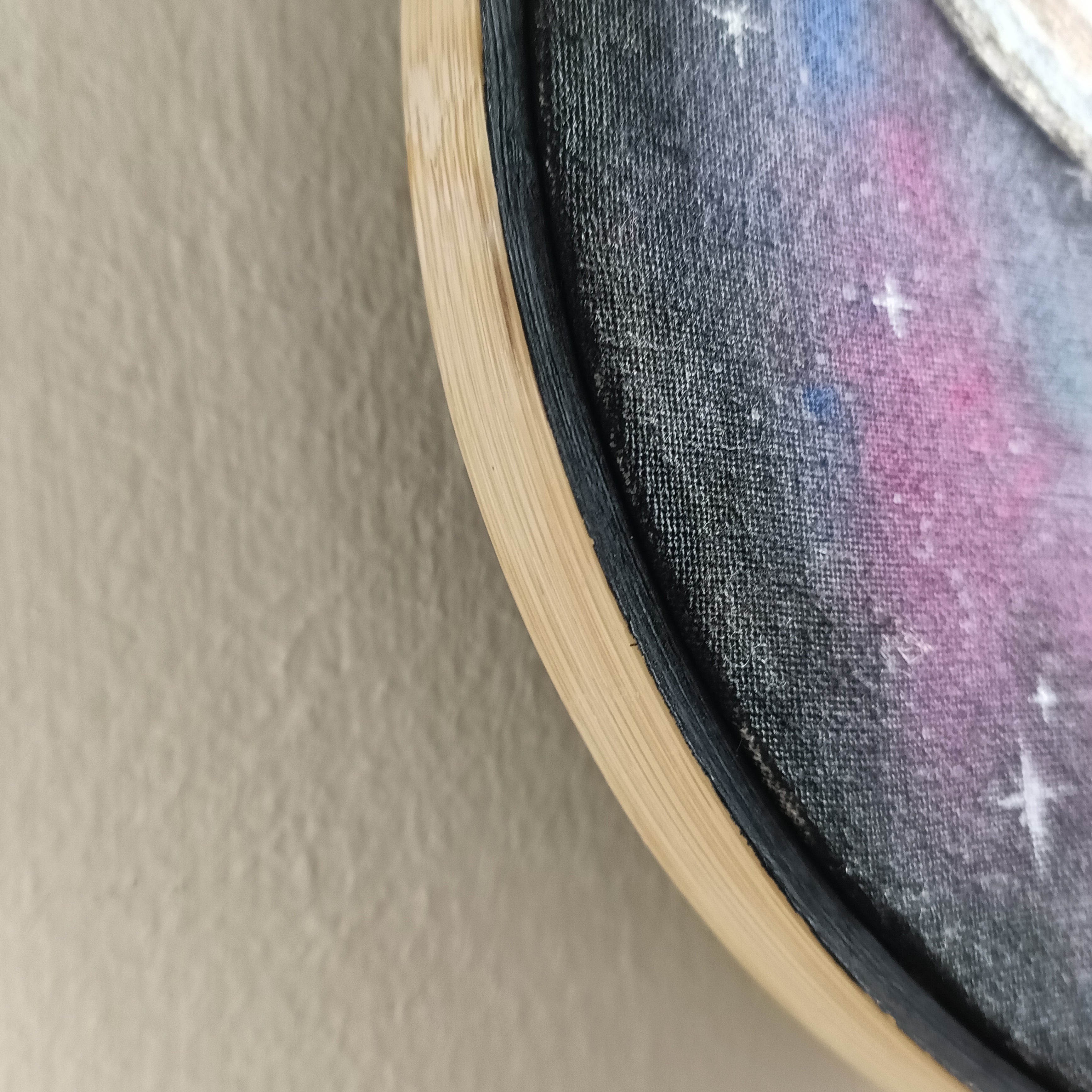 Close-up of painted part of embroidery hoop and painted canvas texture.