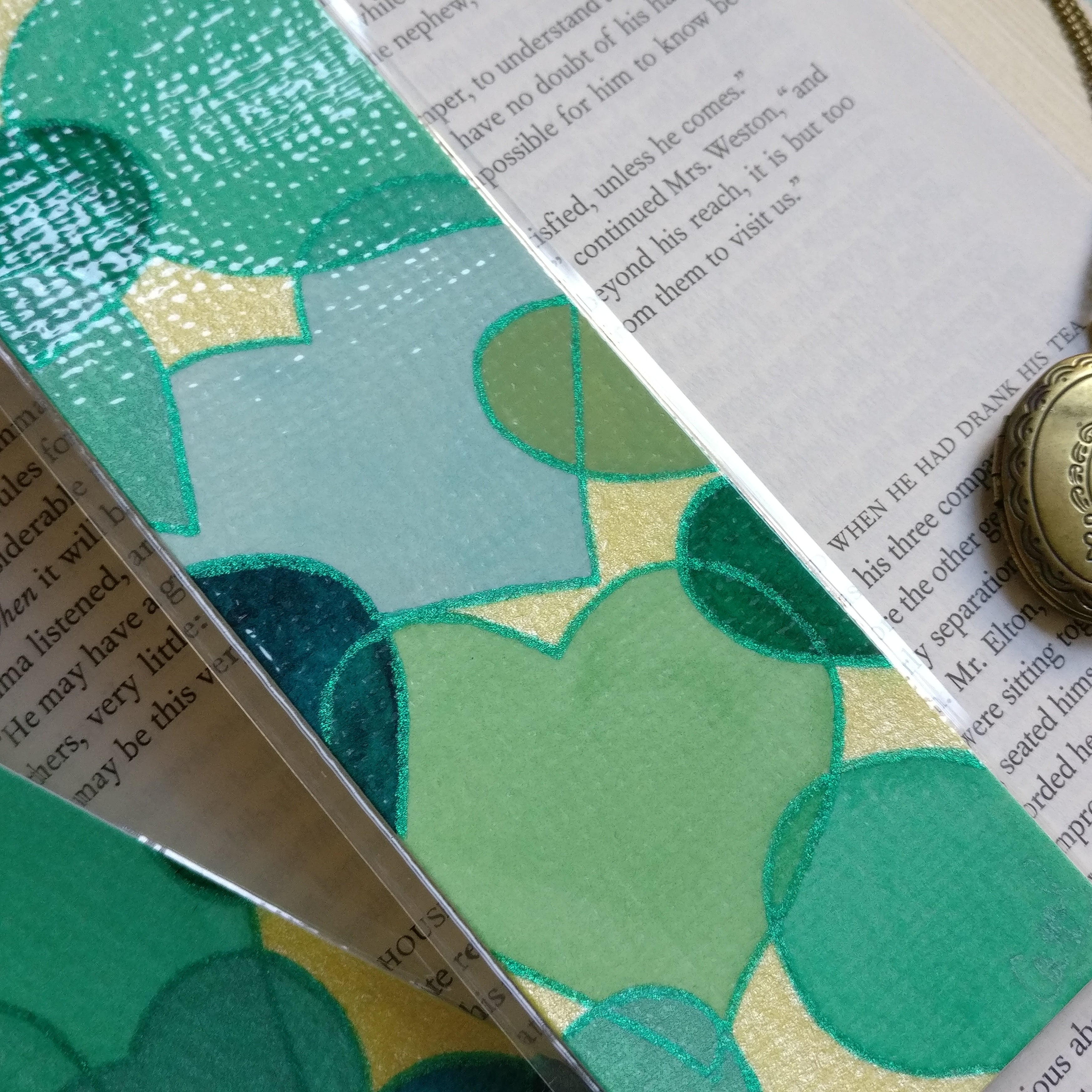 Close-up of a green watercolour hearts bookmarks with glitter green outlines.