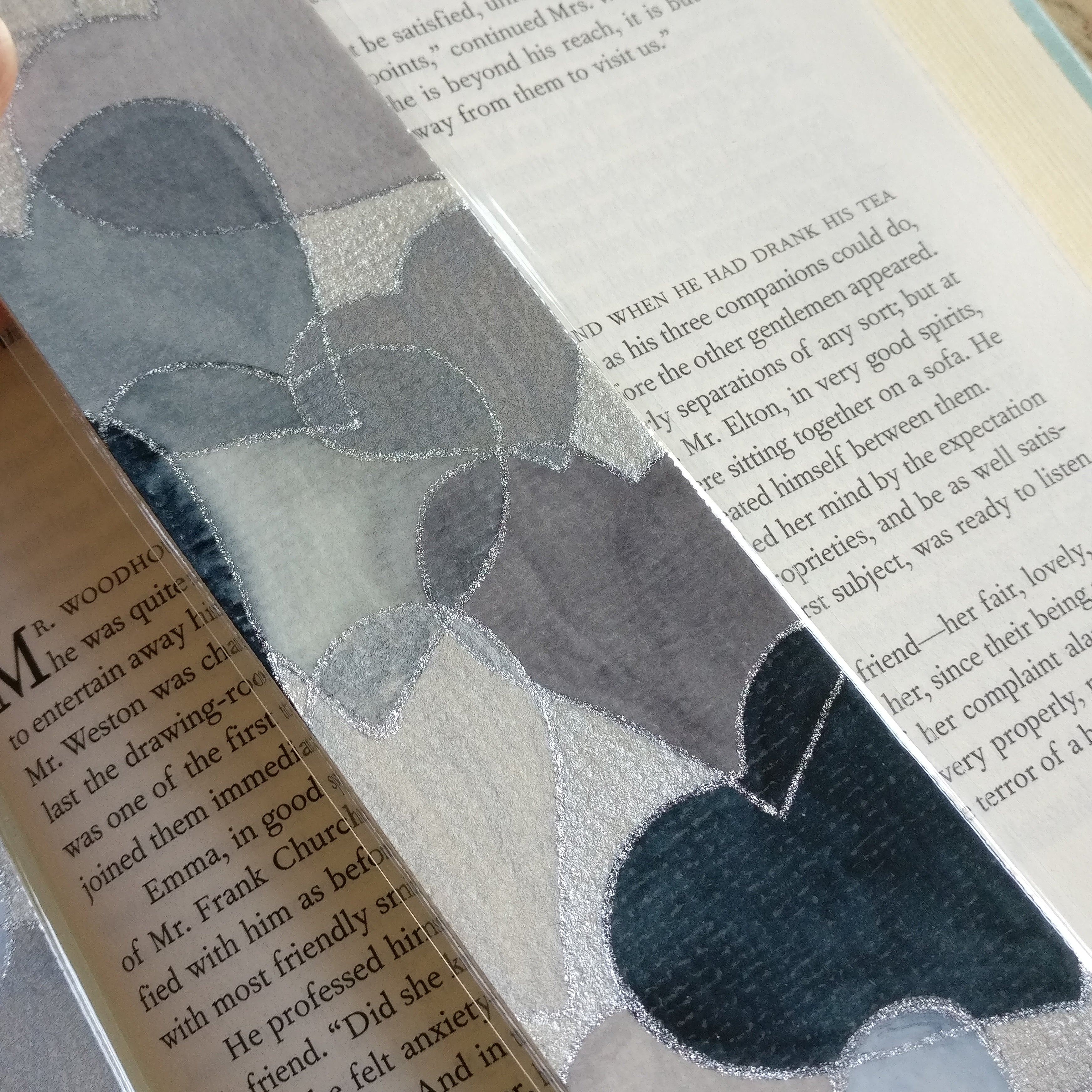 Close-up of grey watercolour hearts bookmark with glitter silver outlines.