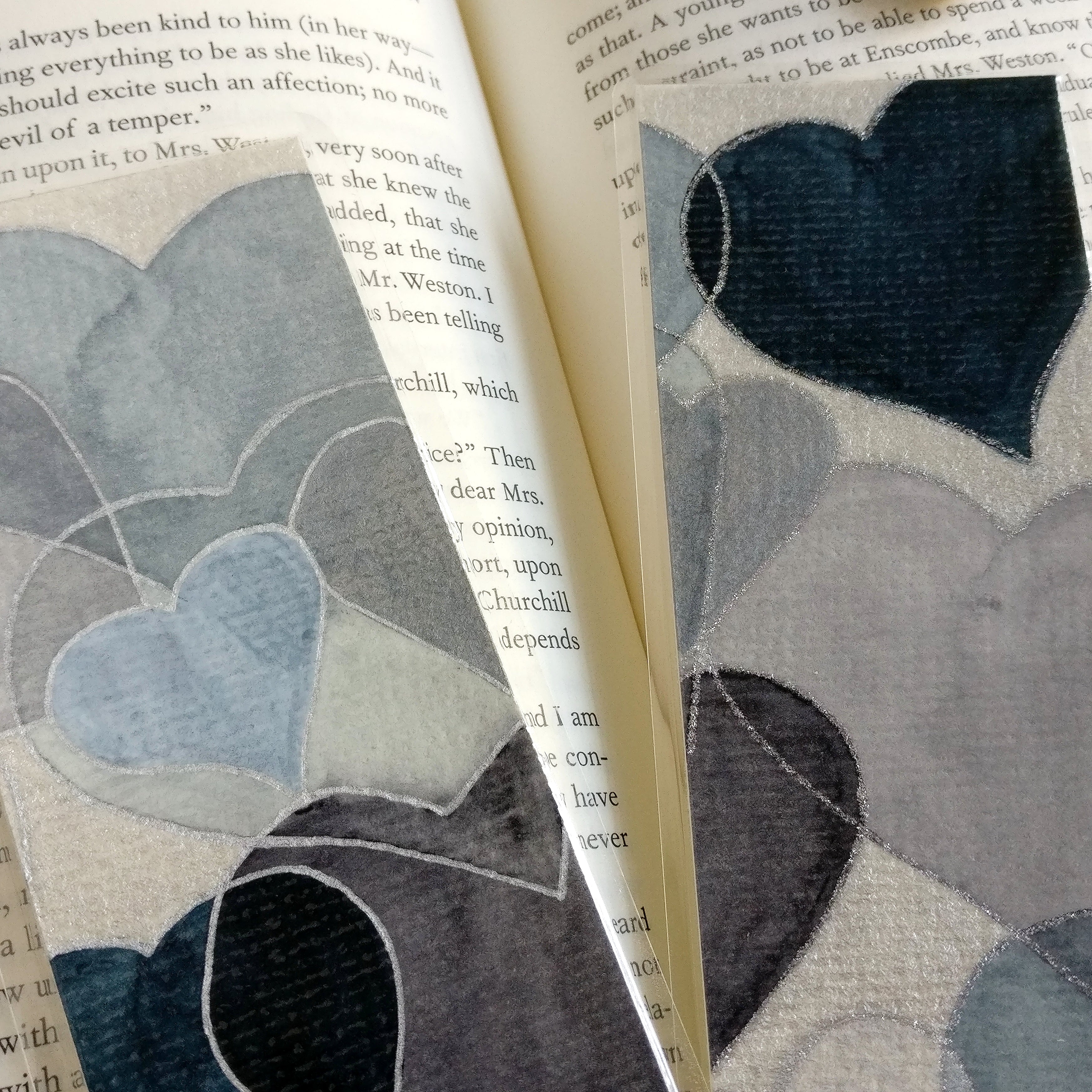 Close-up of two grey watercolour hearts bookmarks with each metallic silver and glitter silver outlines for comparison.