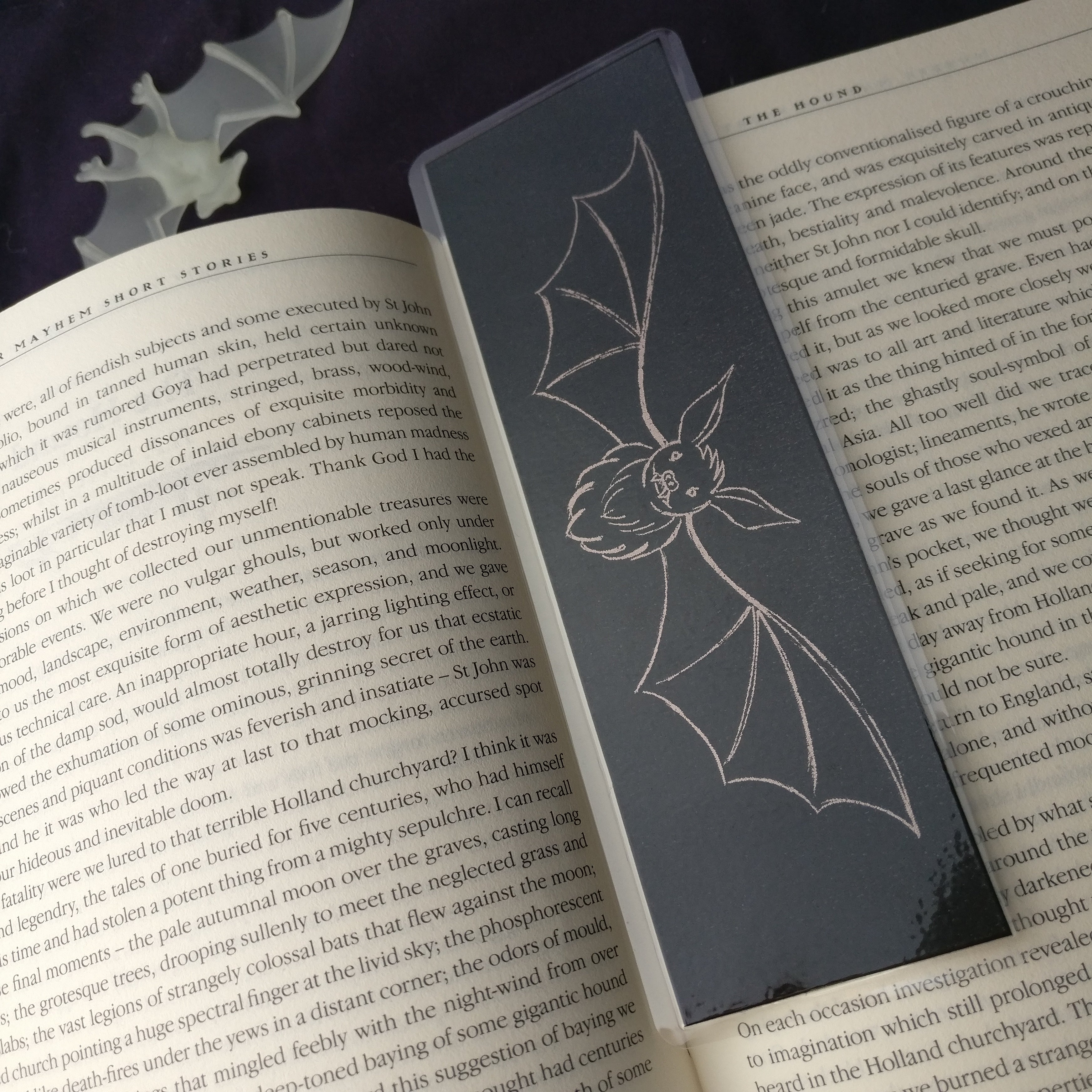 Medium Shadow Bat Bookmark on an open book, closer view showing the soft foil shine.