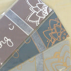 Close-up of three packaging backings, one of each colour variation, from top left to bottom right: silver, copper, gold.