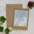 The Dog Mail greeting card with silver foil, laid in front of a kraft envelope.