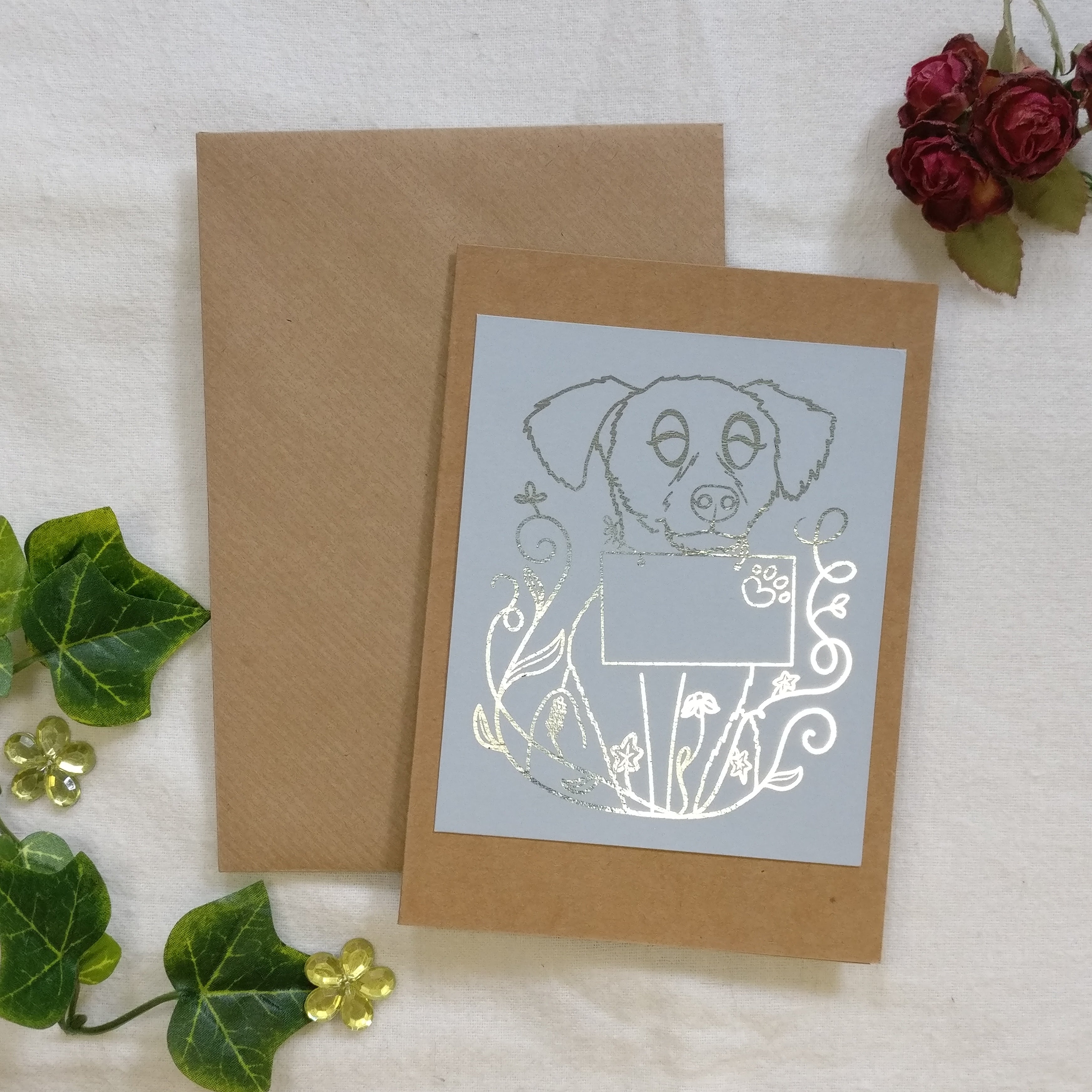 The Dog Mail greeting card with silver foil, laid in front of a kraft envelope.