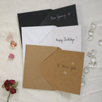Example photo of the three different card and envelope colours that are available within this shop, with writing samples in black and/or white on the cards' blank insides.