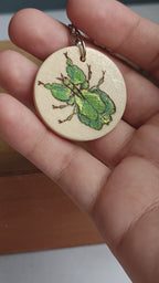 Video of the woodburned and painted details of the walking leaf insect keychain, showing the shimmer details.