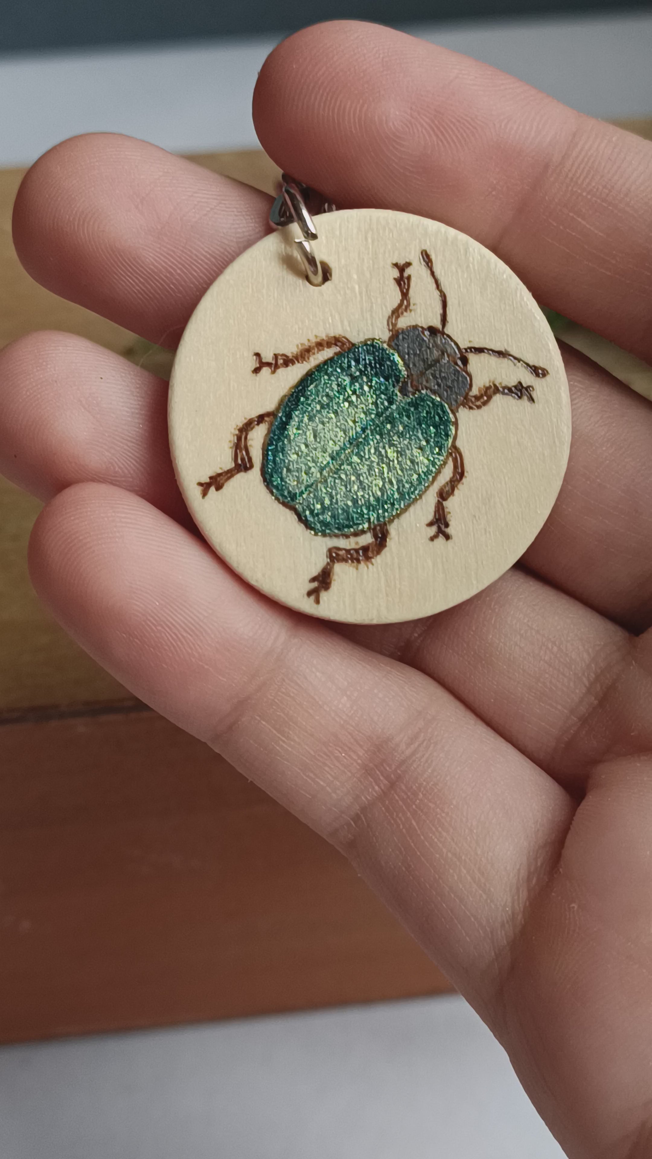 Video close-up of the blue beetle keyring, showing the colour-changing shimmer details and woodburned textures.
